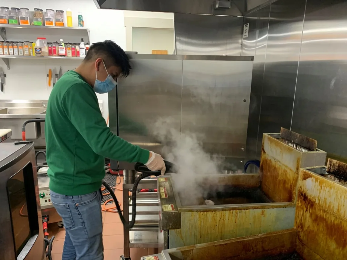 Steam cleaning institutional kitchen cooking equipment for a Cobb County corporate campus cafeteria